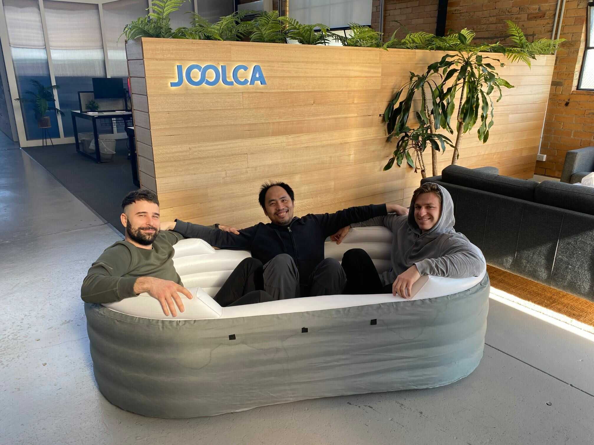 3 men sitting in an unfilled blowup pool